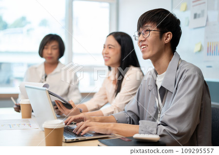 A happy young Asian businessman or male engineer developer is in the meeting with his team. A happy young Asian businessman or male engineer developer is in the meeting with his team. 109295557