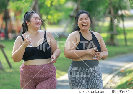 Cheerful two women overweight in sportswear have fun exercising in garden Cheerful two women overweight in sportswear have fun exercising in garden 109295625