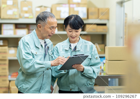 Middle-aged male and female workers packing in a warehouse Middle-aged male and female workers packing in a warehouse 109296267