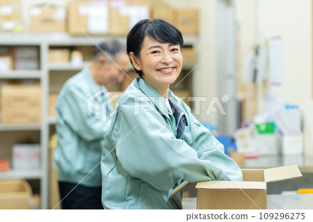 Middle-aged male and female workers packing in a warehouse 109296275