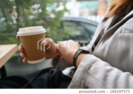 Businesswoman looking on her wrist watch while sitting near office window 109297573