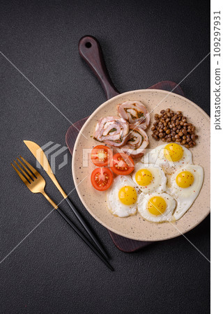 Delicious nutritious breakfast of fried quail eggs, bacon, legumes and cherry tomatoes 109297931