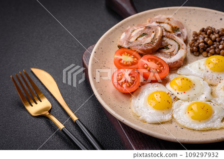 Delicious nutritious breakfast of fried quail eggs, bacon, legumes and cherry tomatoes 109297932