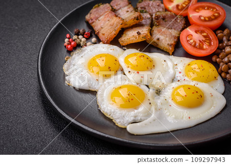 Delicious nutritious breakfast of fried quail eggs, bacon, legumes and cherry tomatoes Delicious nutritious breakfast of fried quail eggs, bacon, legumes and cherry tomatoes 109297943