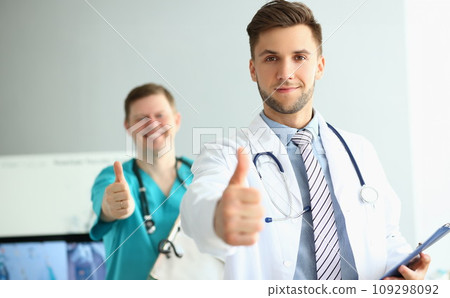 Two doctors gesture thumbs up in clinic recommending medical services Two doctors gesture thumbs up in clinic recommending medical services 109298092