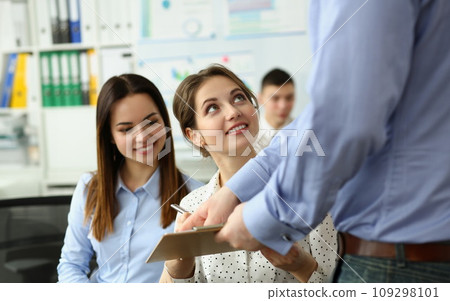 Boss or coach mentor coach showing young female trainee document on training. Boss or coach mentor coach showing young female trainee document on training. 109298101