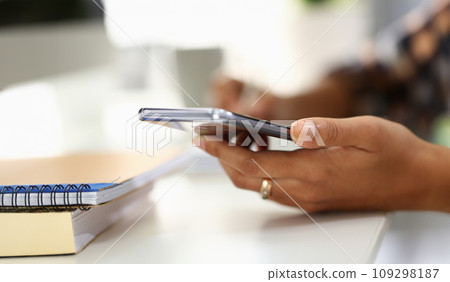 Student writes in notebook and holds smartphone Student writes in notebook and holds smartphone 109298187