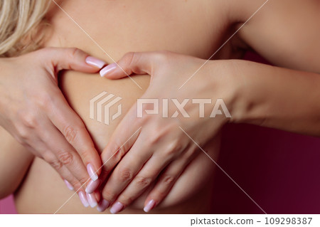 A sexy girl on a beautiful chest depicts a heart. Valentine's Day and Heart Care 109298387