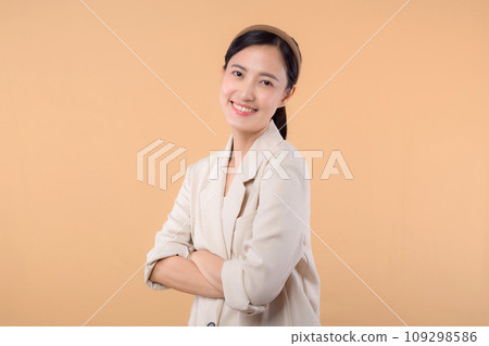 Studio portrait of happy successful confident young asian business woman. Beautiful young lady in white jacket smiling at camera standing isolated on solid beige colour copyspace background Studio portrait of happy successful confident young asian business woman. Beautiful young lady in white jacket smiling at camera standing isolated on solid beige colour copyspace background 109298586
