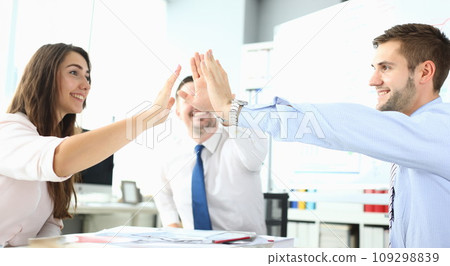 Happy business team high five in office Happy business team high five in office 109298839