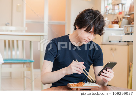 Young man eating convenience store bento at home Young man eating convenience store bento at home 109299057