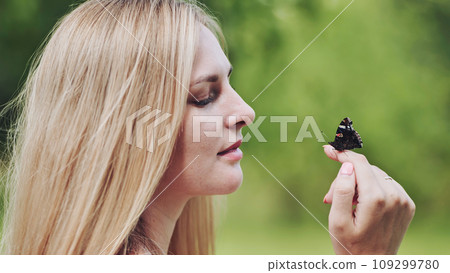 The girl gently enjoys the butterfly that flew to her. 109299780