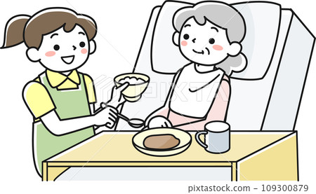 A senior woman eating in bed and a female staff member assisting her A senior woman eating in bed and a female staff member assisting her 109300879