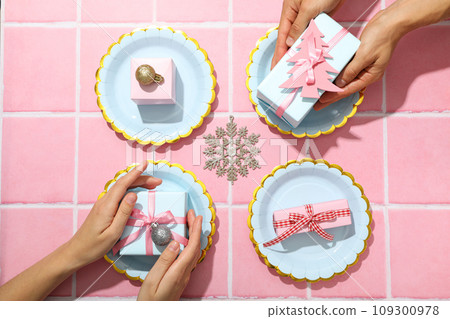 Plates and gift boxes in hands on pink background, top view Plates and gift boxes in hands on pink background, top view 109300978