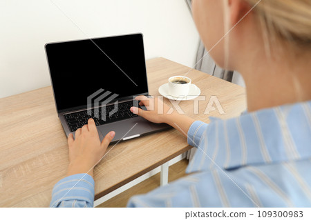 A woman with a cup of coffee is working on a laptop 109300983