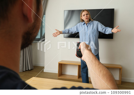 The woman does not allow the man to watch TV The woman does not allow the man to watch TV 109300991