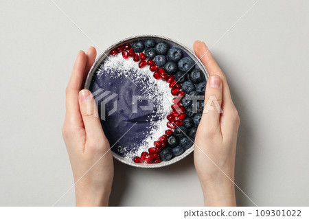 Bowl with smoothie in female hands on gray background, top view Bowl with smoothie in female hands on gray background, top view 109301022