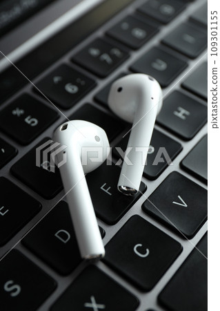 White, headphones, in-ears on the laptop keyboard. 109301155