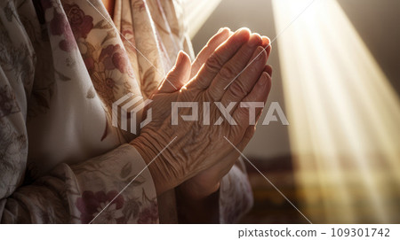 Lifestyle closeup shot of grandma prays with folded hands under the sun light. Play of light and shadow 109301742