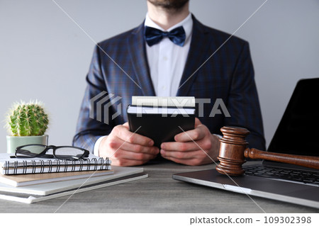 Man in suit, notepads, wooden hammer and laptop on gray background Man in suit, notepads, wooden hammer and laptop on gray background 109302398