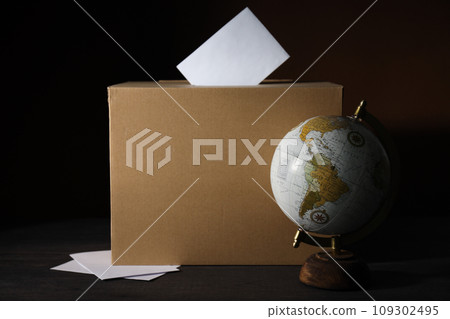 Voting box and globe on wooden table on black background 109302495