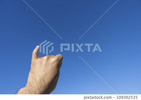 A man's hand cutting his finger against the blue sky (30s, Japanese) 109302535