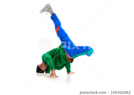 Stylishly dressed man performing freestyle, breakdance, standing on hands raised up legs against white background. Swipe. Stylishly dressed man performing freestyle, breakdance, standing on hands raised up legs against white background. Swipe. 109302662