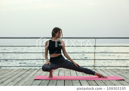 Young woman on yoga mat on wooden floor outdoors, space for text 109303195