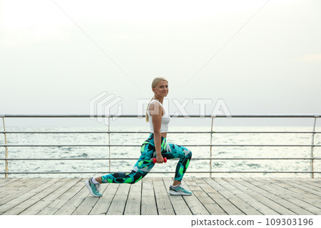 Young woman with dumbbells on wooden floor outdoors Young woman with dumbbells on wooden floor outdoors 109303196