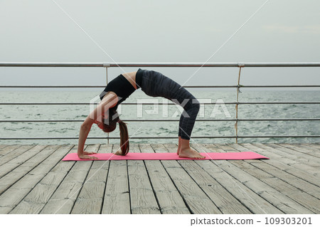 Young woman on yoga mat on wooden floor outdoors Young woman on yoga mat on wooden floor outdoors 109303201