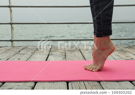 Female legs on yoga mat on wooden floor outdoors, space for text Female legs on yoga mat on wooden floor outdoors, space for text 109303202