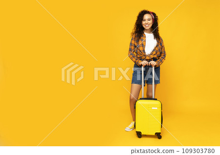 Young attractive girl with a yellow suitcase Young attractive girl with a yellow suitcase 109303780