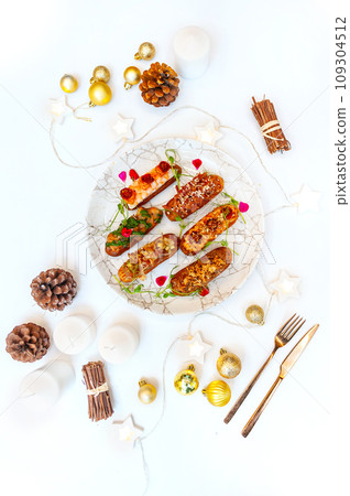 Eclairs on a marble plate on a background with Christmas or New Year decor Eclairs on a marble plate on a background with Christmas or New Year decor 109304512
