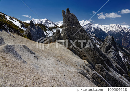 Iruka Rock on the Tsubakudake ridgeline in the Northern Alps and Mt. Yarigatake with remaining snow 109304618