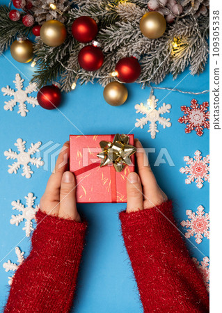 Christmas and New Year gifts. Gift in hands on blue background, top view 109305338