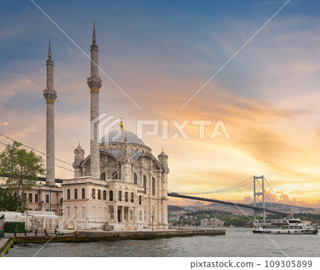 Ortakoy Mosque next to Bosphorus Bridge, with glistening minarets and domes at sunset in Ortakoy, Istanbul, Turkey 109305899