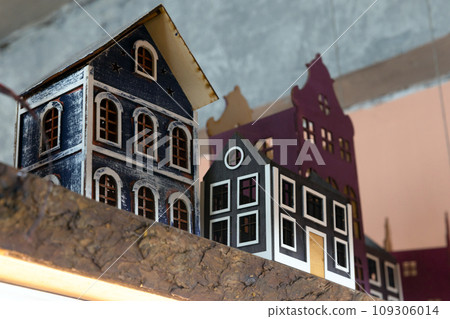 Decorative colorful wooden toy houses stand in a row on a shelf 109306014