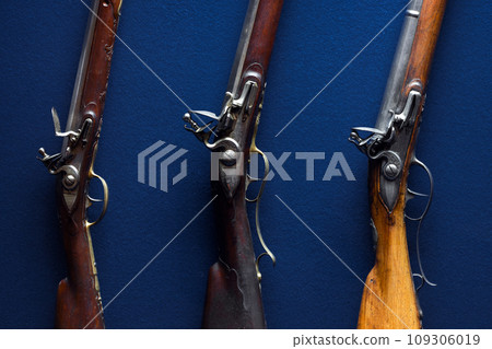 Flintlocks of 18th-century rifles over deep blue velvet background Flintlocks of 18th-century rifles over deep blue velvet background 109306019