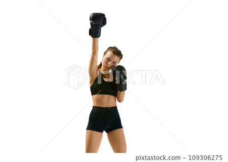 Poised and ready boxer, her eyes burning with determination, stands poised for action against white studio background. Poised and ready boxer, her eyes burning with determination, stands poised for action against white studio background. 109306275