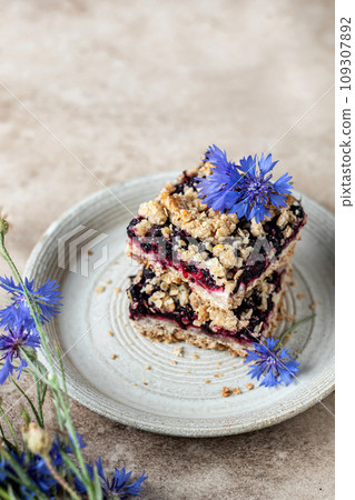 Baked oatmeal squares with fresh blueberry on beige background with cornflowers close up, copy space. Menu, recipe Baked oatmeal squares with fresh blueberry on beige background with cornflowers close up, copy space. Menu, recipe 109307892