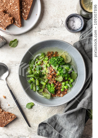 Vegetarian minestrone soup with green vegetables and lentils in gray plate on textured background, top view Vegetarian minestrone soup with green vegetables and lentils in gray plate on textured background, top view 109307896