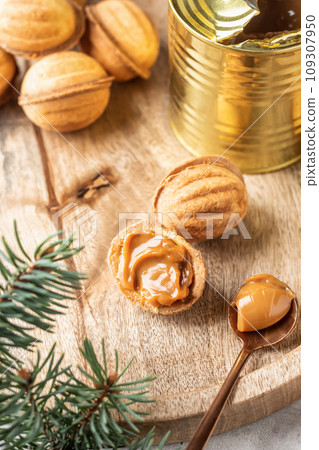 Tasty walnut shaped cookies with boiled condensed milk on wooden board with fir branches. Process of making traditional christmas cookies oreshki Tasty walnut shaped cookies with boiled condensed milk on wooden board with fir branches. Process of making traditional christmas cookies oreshki 109307950