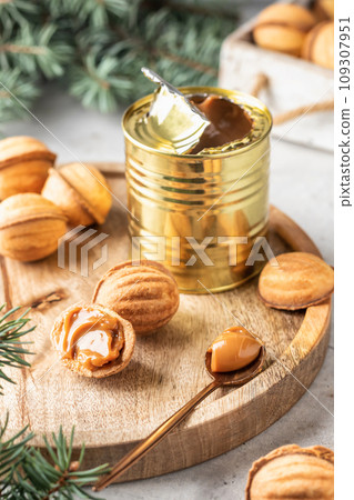 Tasty walnut shaped cookies with boiled condensed milk on wooden board with fir branches. Process of making traditional christmas cookies oreshki Tasty walnut shaped cookies with boiled condensed milk on wooden board with fir branches. Process of making traditional christmas cookies oreshki 109307951