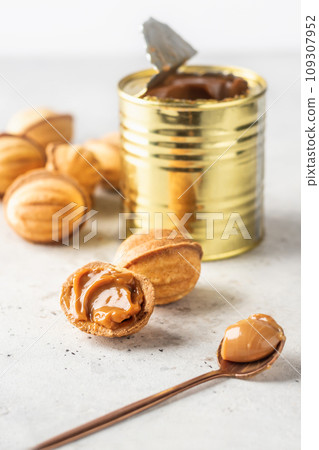 Tasty walnut shaped cookies with boiled condensed milk on white background. Christmas or new year traditional cookies Tasty walnut shaped cookies with boiled condensed milk on white background. Christmas or new year traditional cookies 109307952