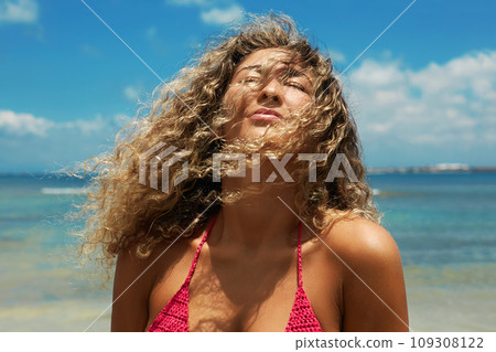 Beautiful happy woman on the beach. Smiling girl in Bikini near sea. Curty Hairstyle 109308122