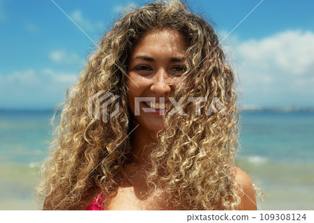Beautiful happy woman on the beach. Smiling girl in Bikini near sea. Curty Hairstyle Beautiful happy woman on the beach. Smiling girl in Bikini near sea. Curty Hairstyle 109308124