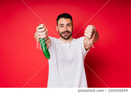 Male hand holding cucumber on red background, space for text Male hand holding cucumber on red background, space for text 109308844