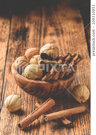 Cinnamon sticks and dried limes in wooden bowl Cinnamon sticks and dried limes in wooden bowl 109310851