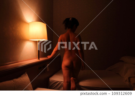 Female nude back pose, body silhouette floating in dark lighting 109312609