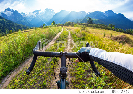 hands on the handlebars of a bicycle of a cyclist riding along a trail in nature. Point of view 109312742